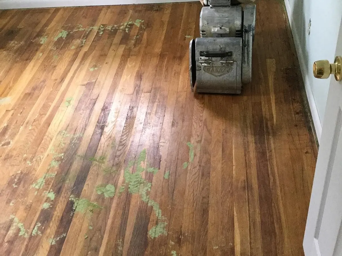 Bedroom hardwood floor with paint spots and a worn finish